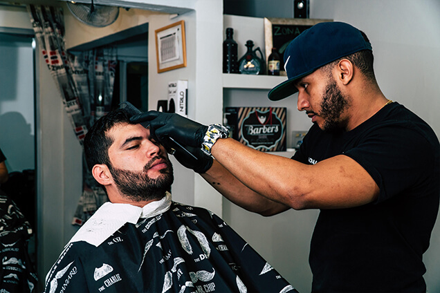 barber working on trimming client beard